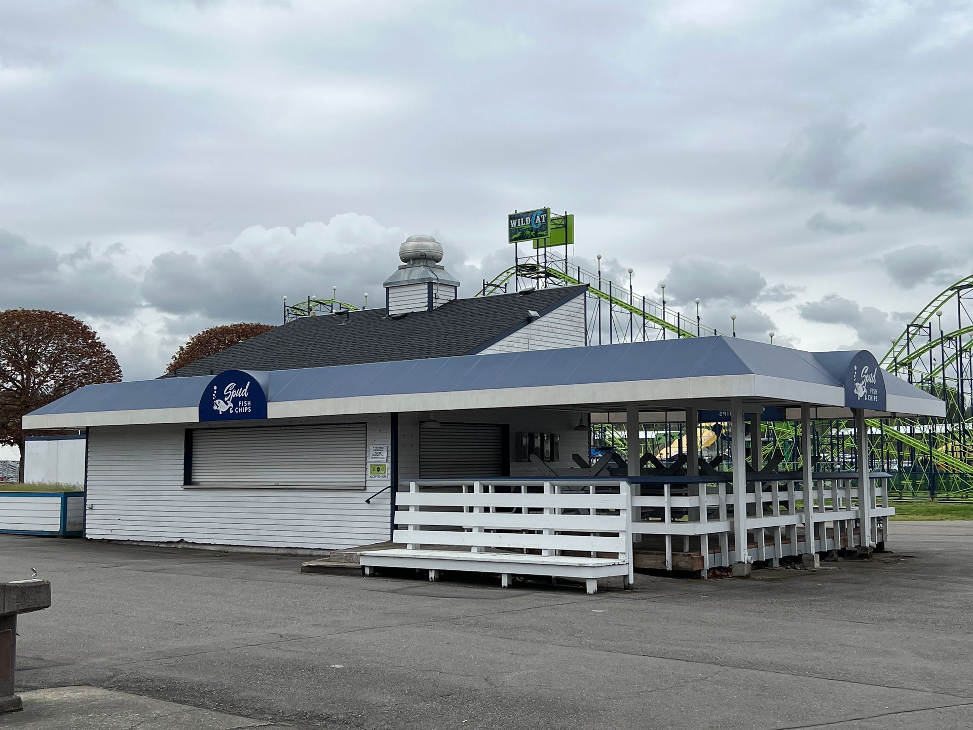 A white building with a blue awning and a roller coaster in the background.