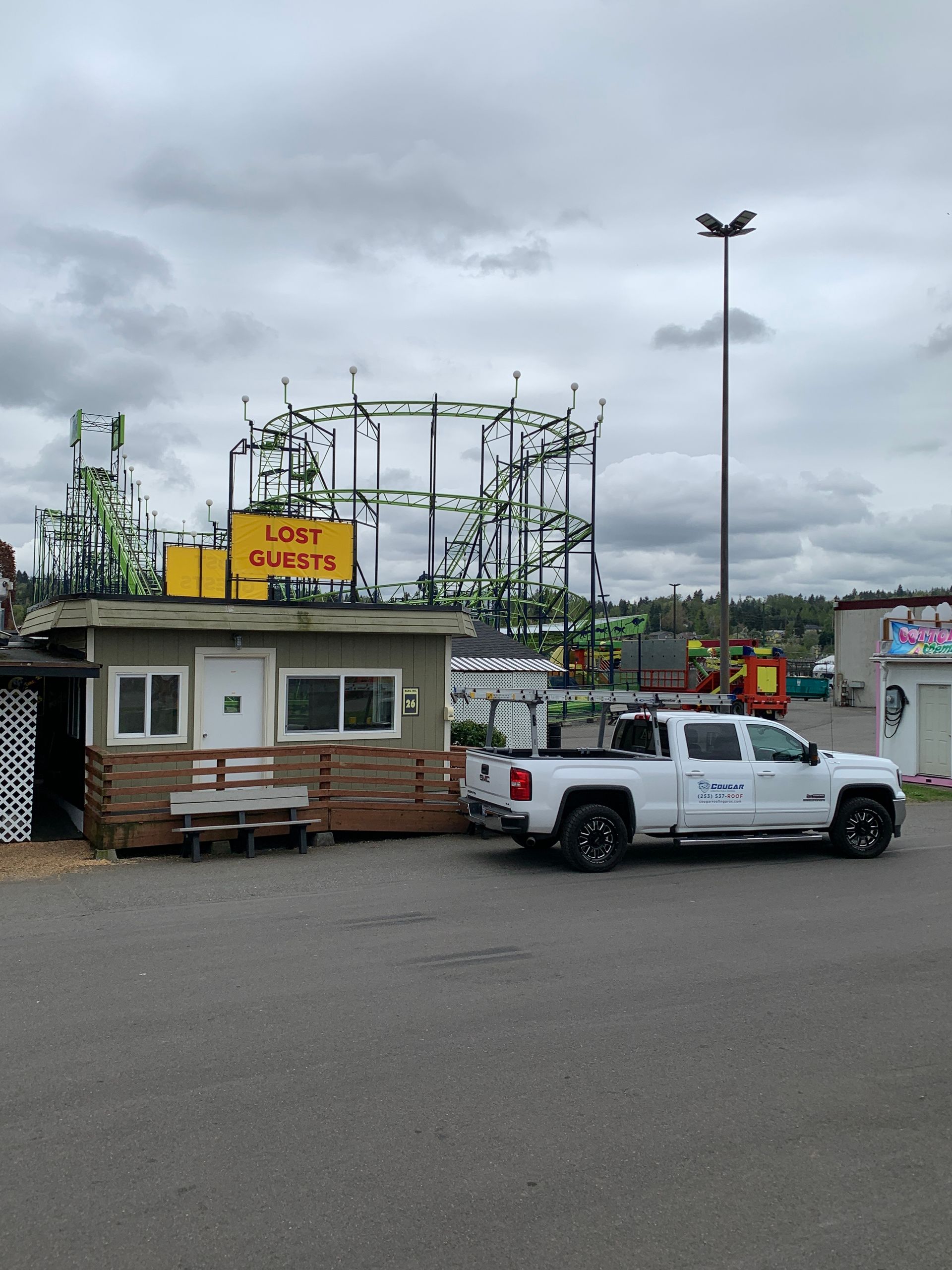 A white truck is parked in front of a building with a yellow sign that says lost quest