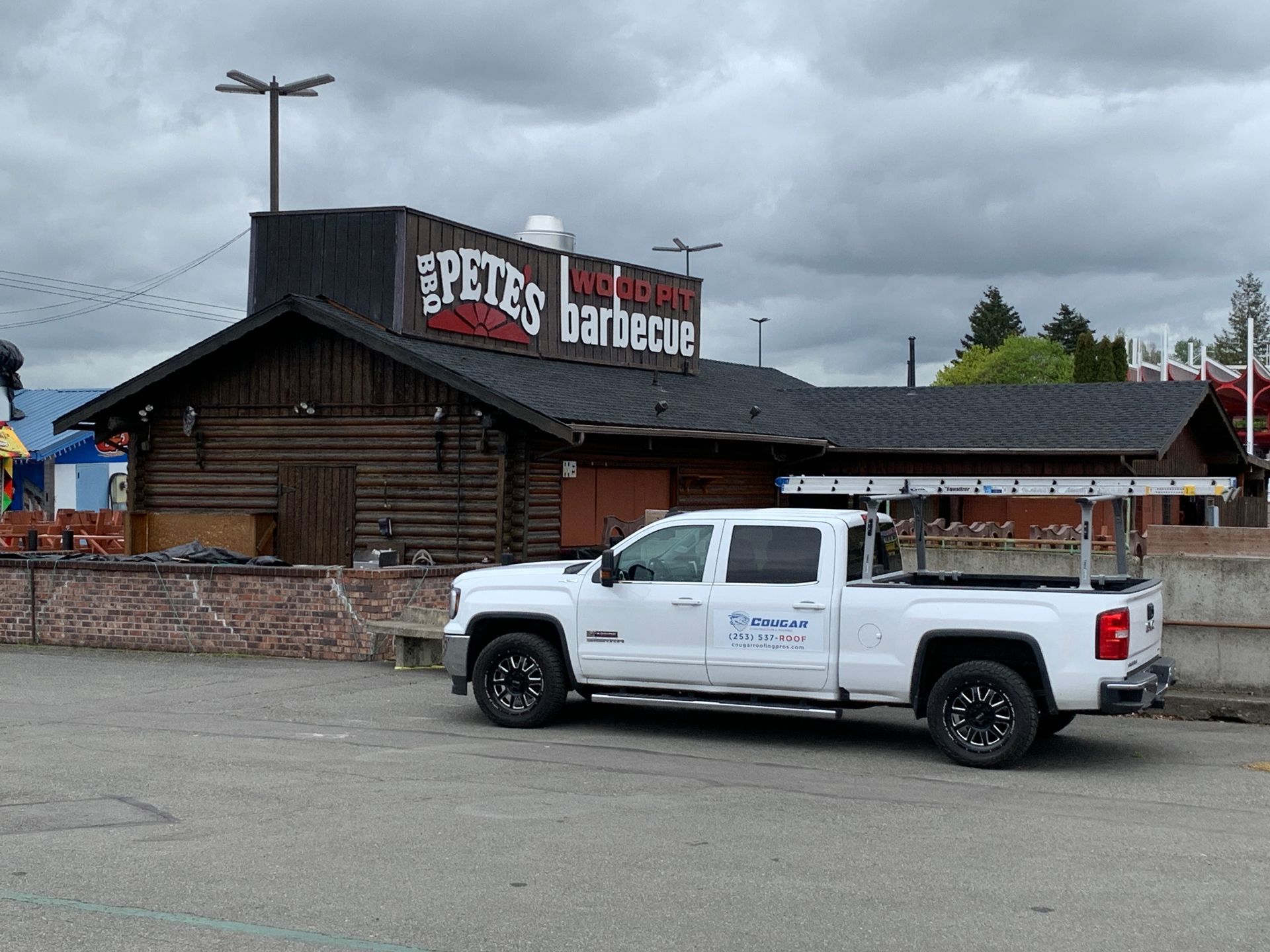 A white truck is parked in front of a barbecue restaurant.