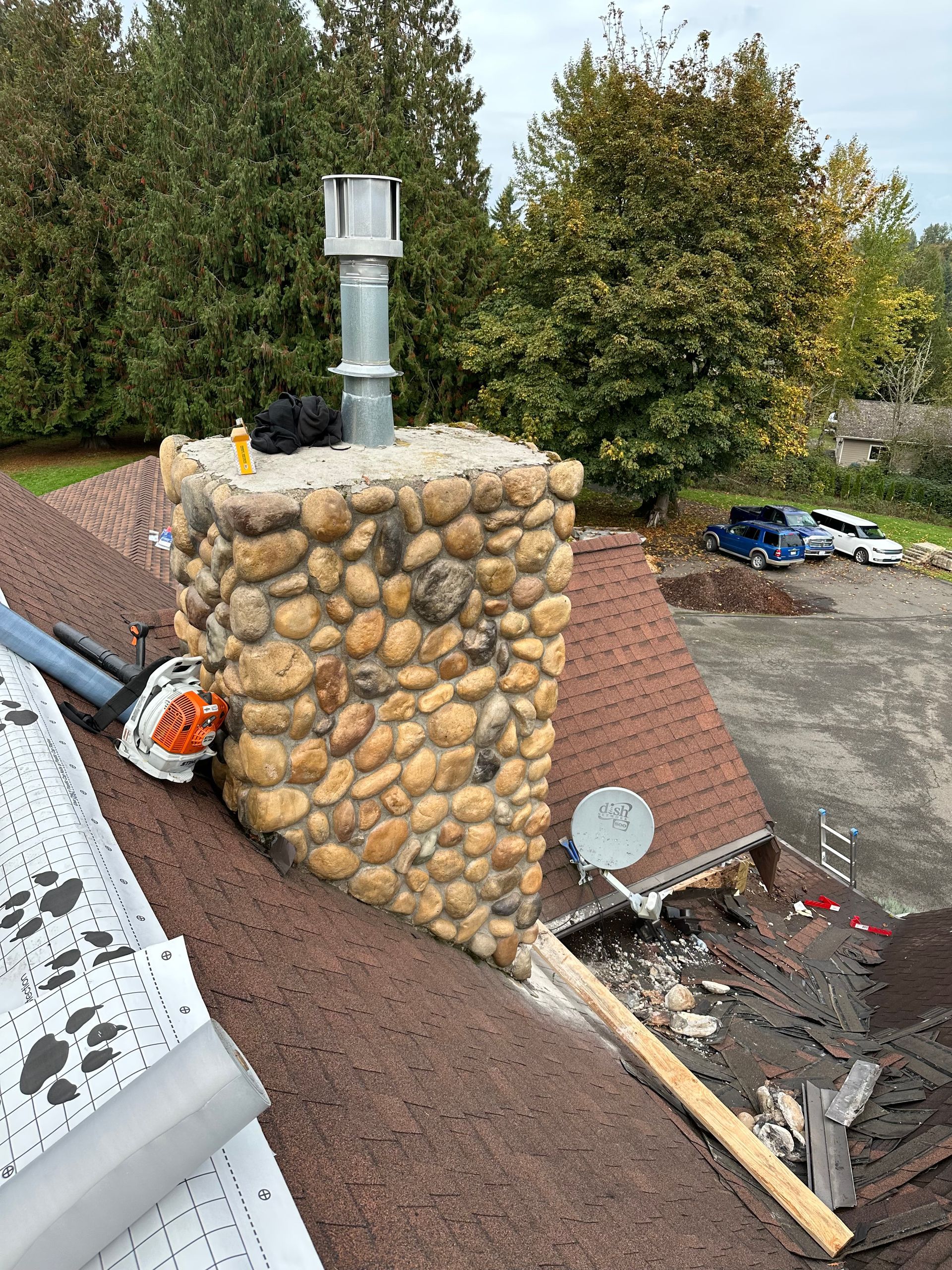 A stone chimney is sitting on top of a roof.