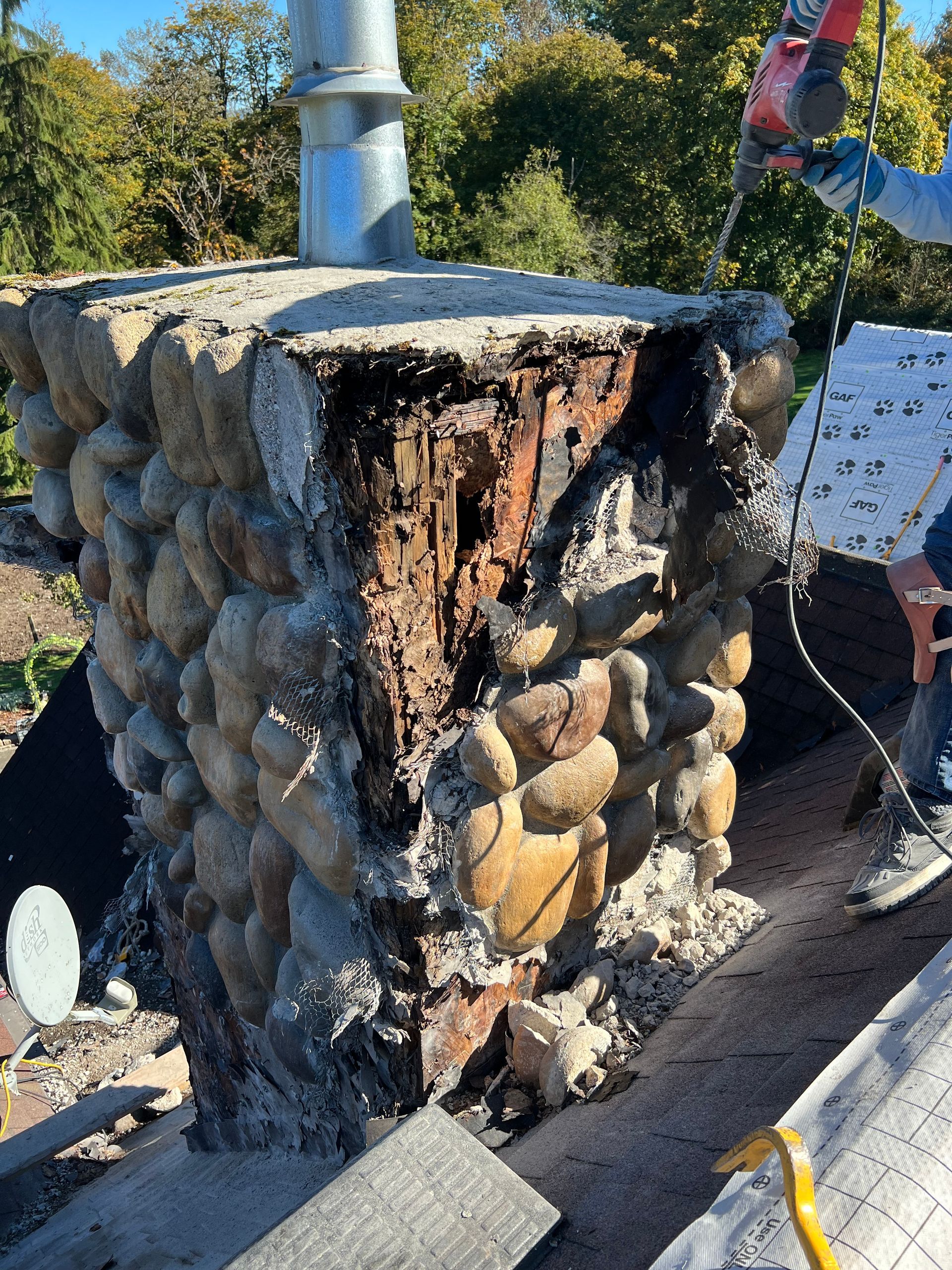 A man is cutting a stone chimney with a circular saw.