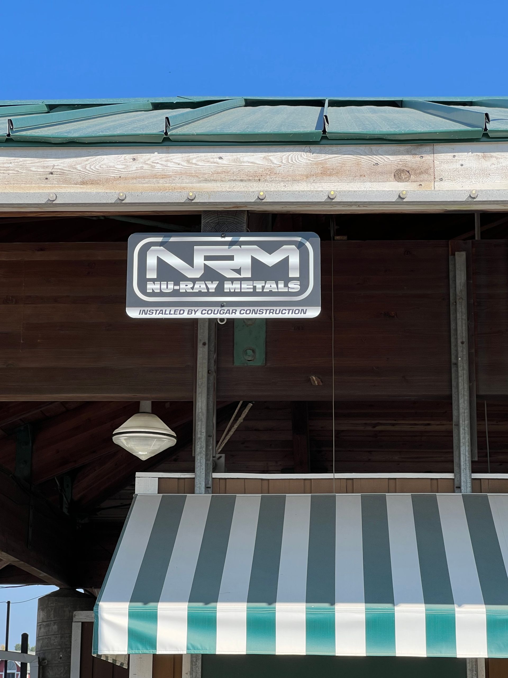 A sign for nrm mobility metals hangs above a striped awning