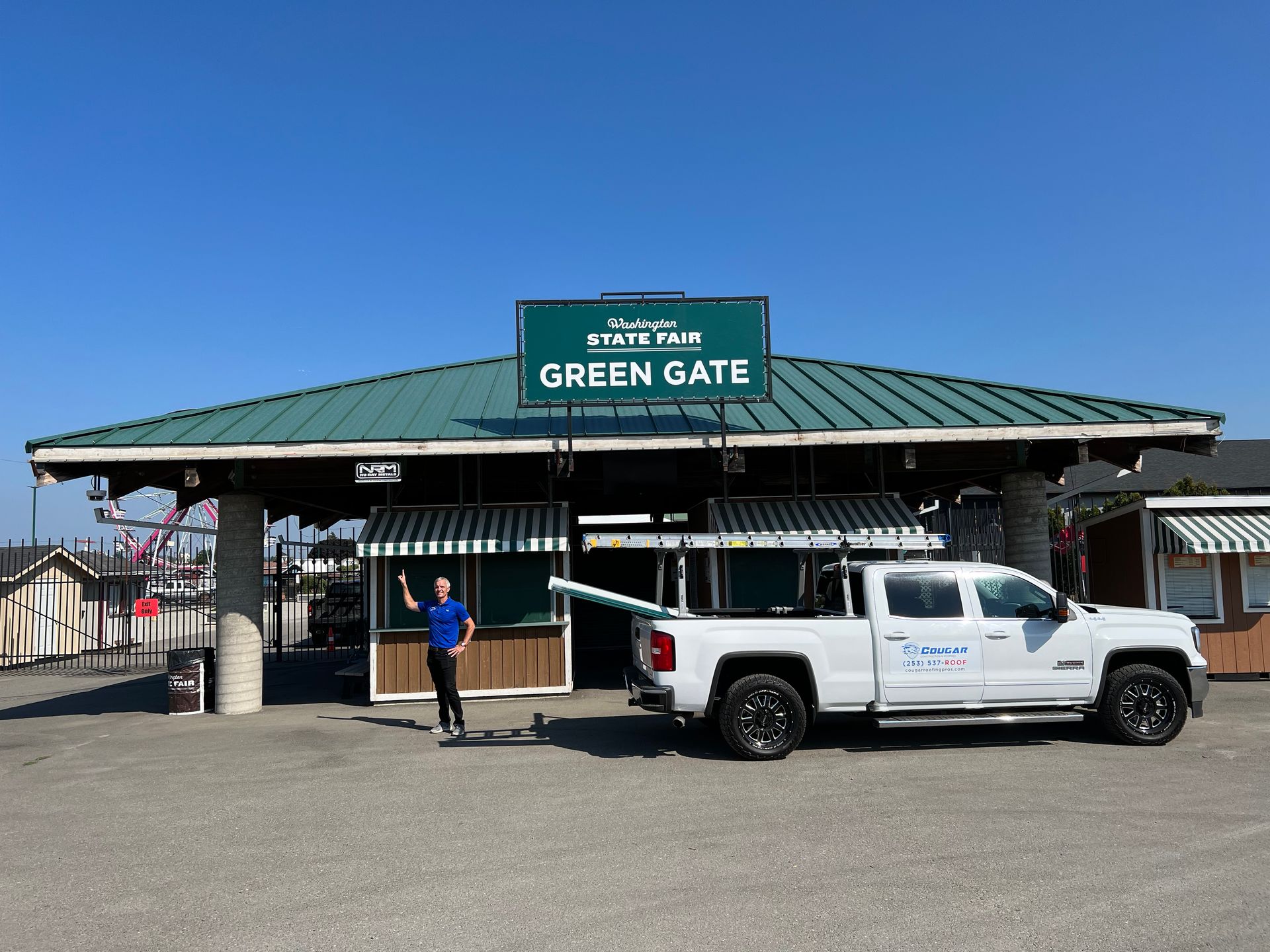 A white truck is parked in front of a building that says green gate