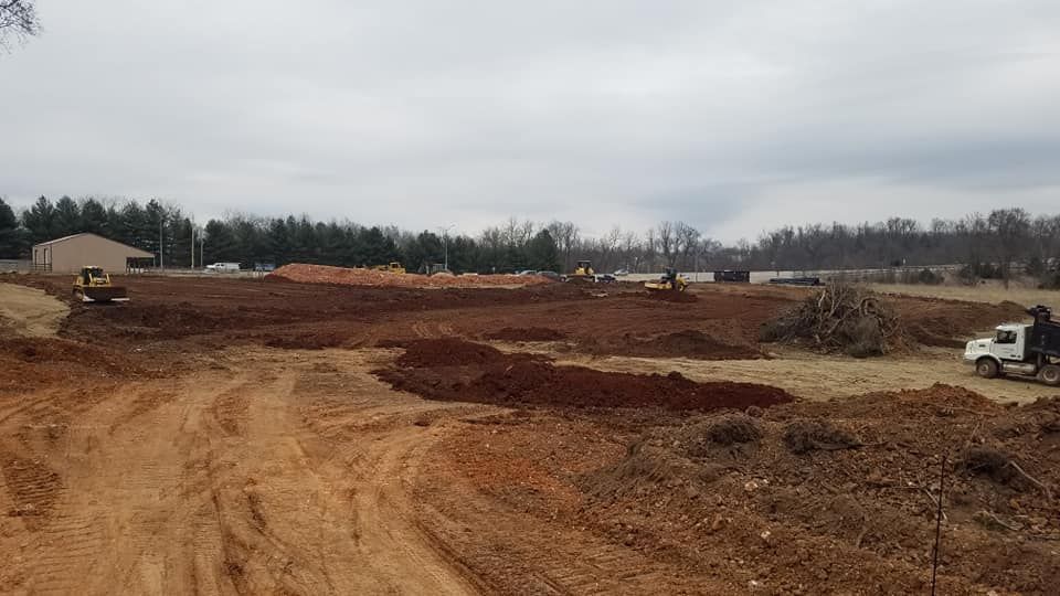 A large dirt field with a white truck parked in the middle of it.