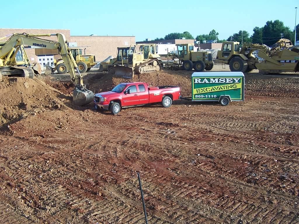 A red truck is parked next to a green trailer that says team city