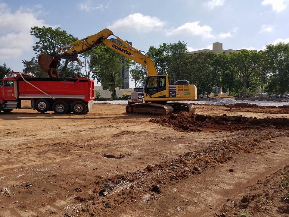 A yellow excavator is loading dirt into a red dump truck.
