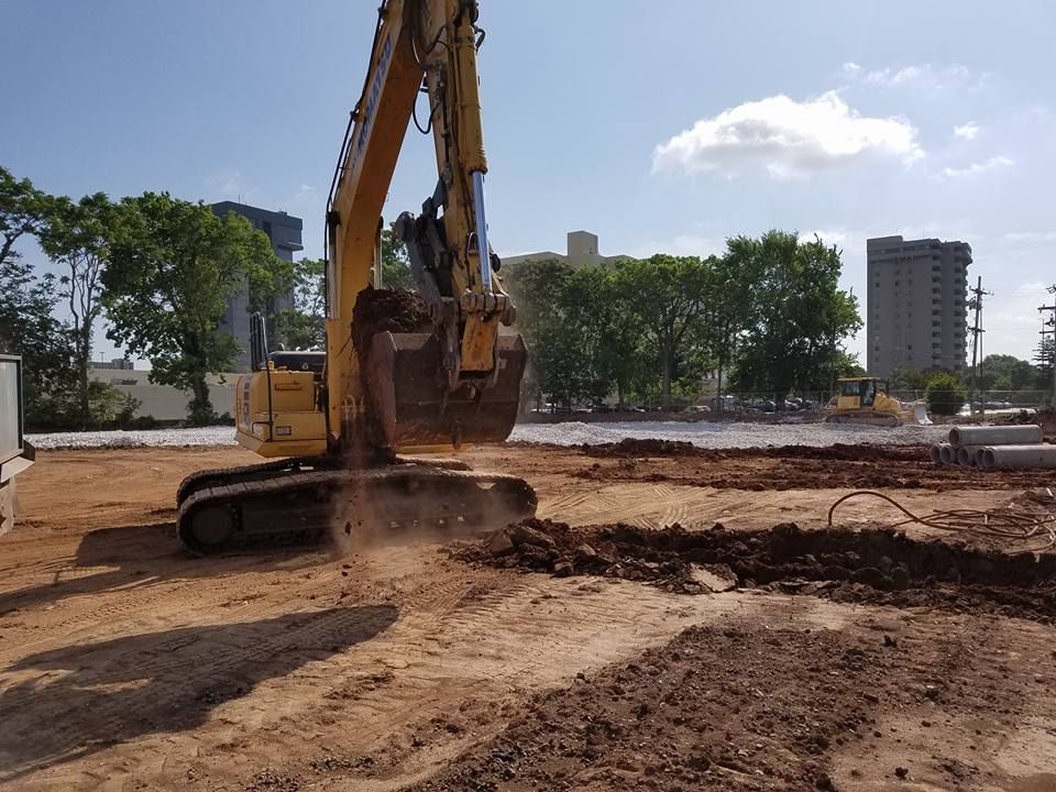 A yellow excavator is digging a hole in a dirt field