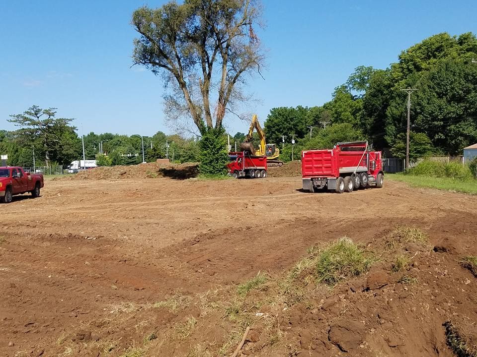 Two red dump trucks are parked in a dirt field