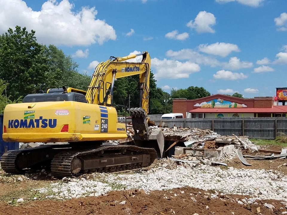 A yellow komatsu excavator is being used to demolish a building