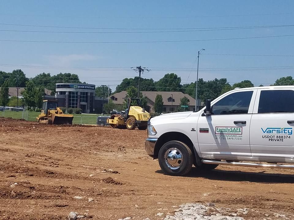 A white vanguard truck is parked in a dirt field