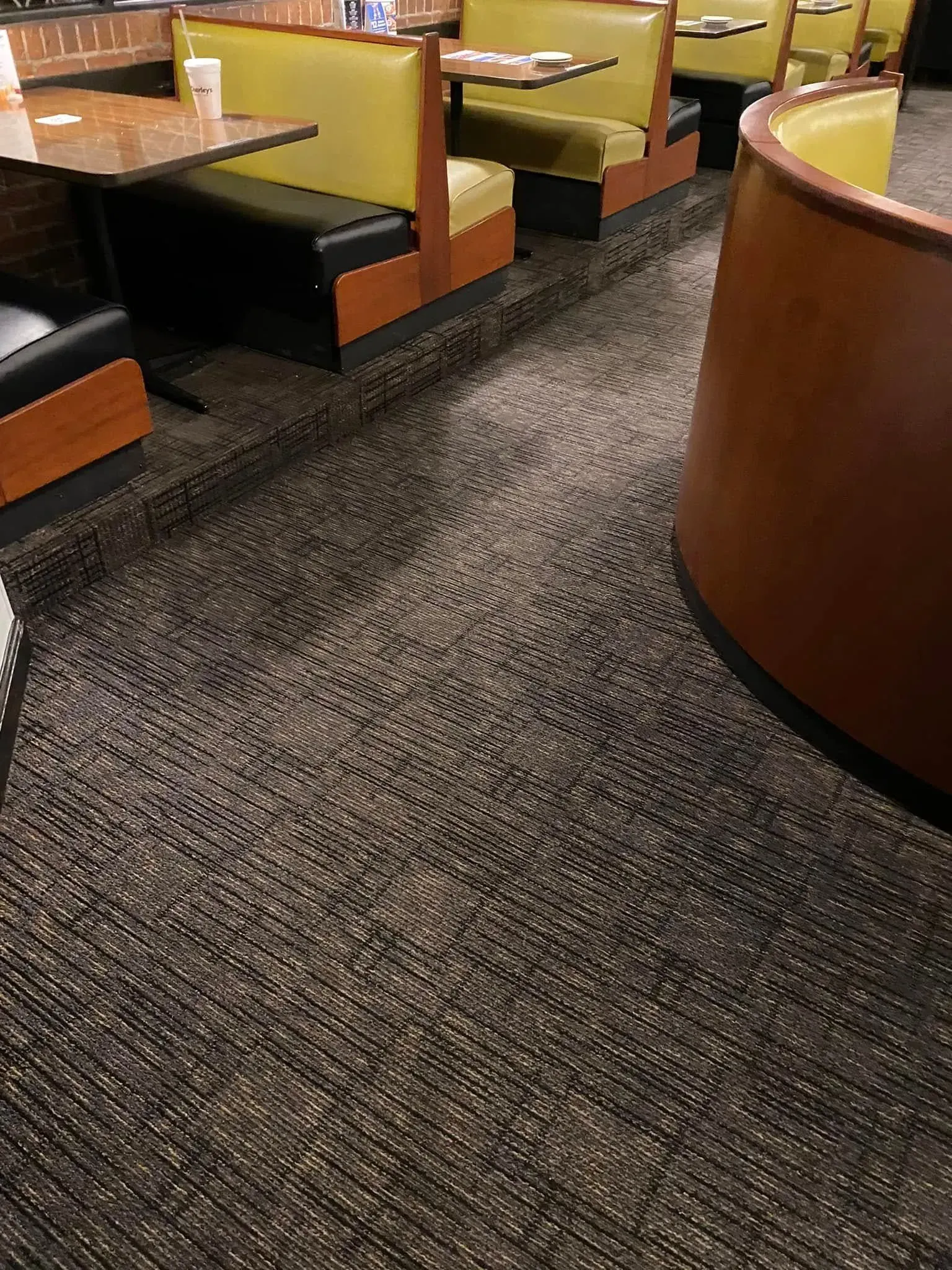 Restaurant booth seating with yellow upholstered benches and dark carpeted floor.