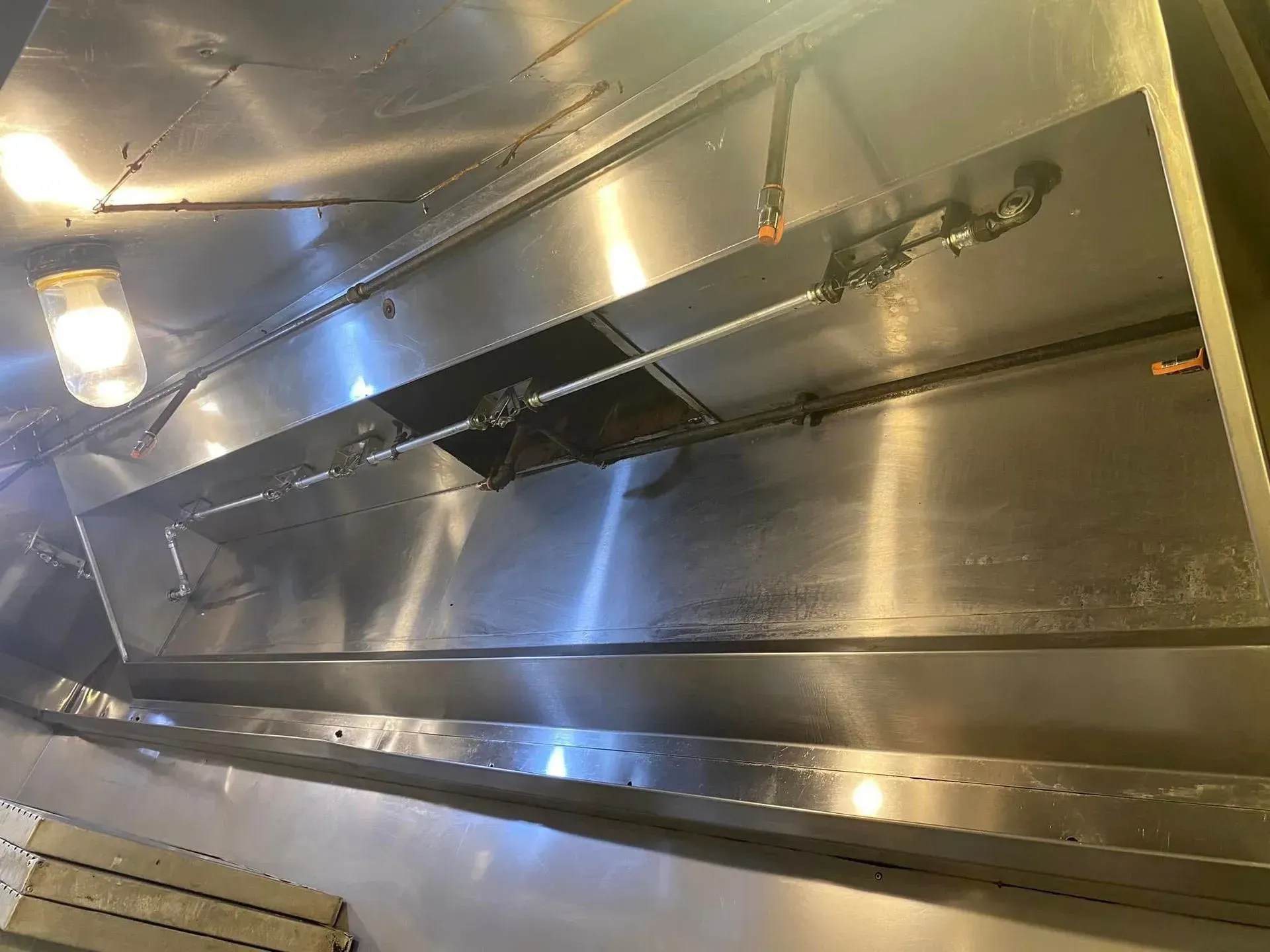 Metal air duct interior with shiny silver panels and a hinged vent opening.