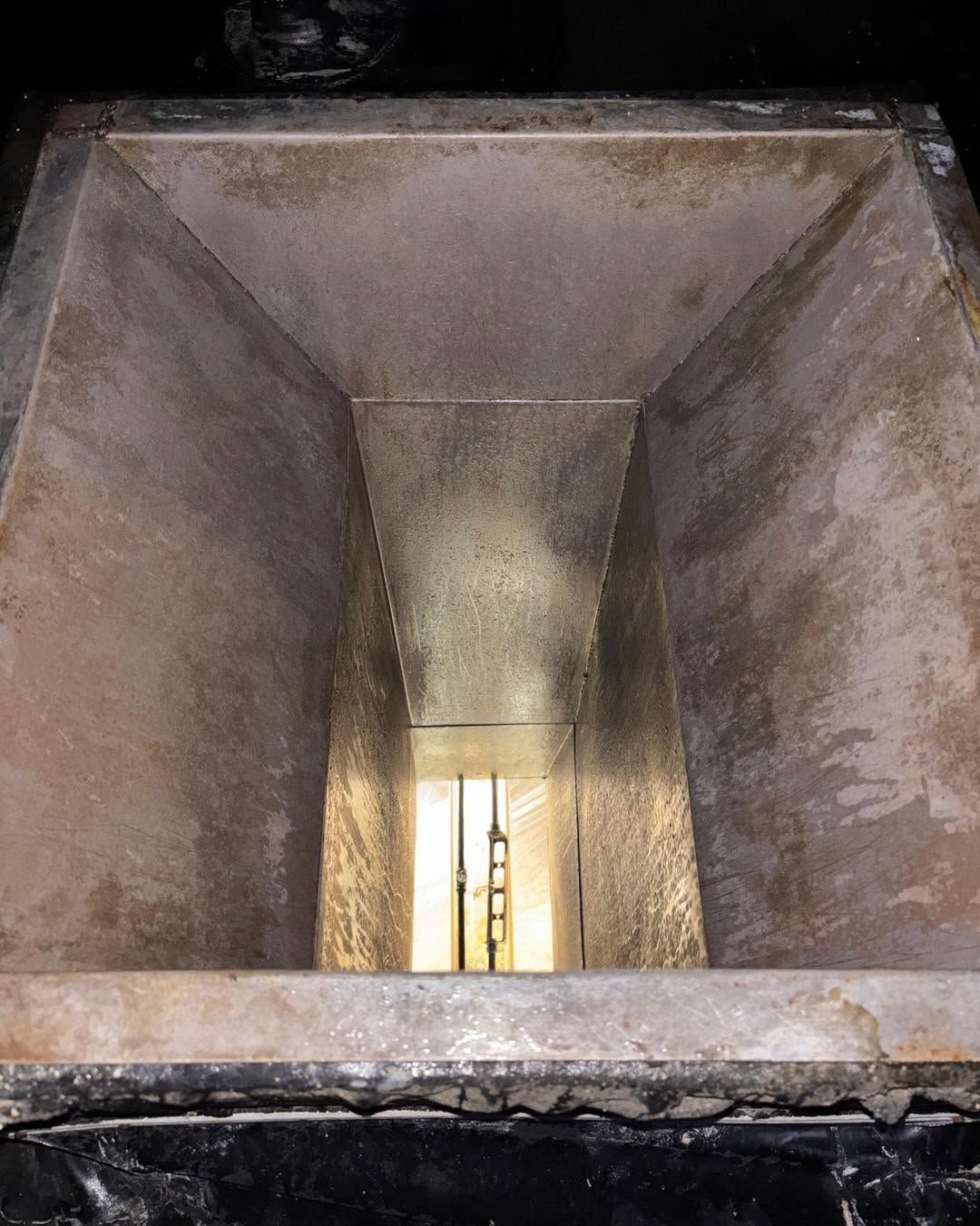 Rusty metal chute with a bright opening at the far end, viewed from inside.