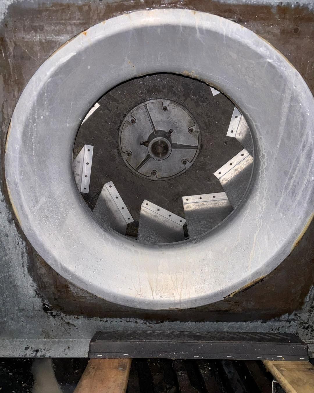Round concrete ventilation fan with metal blades set in a wall opening