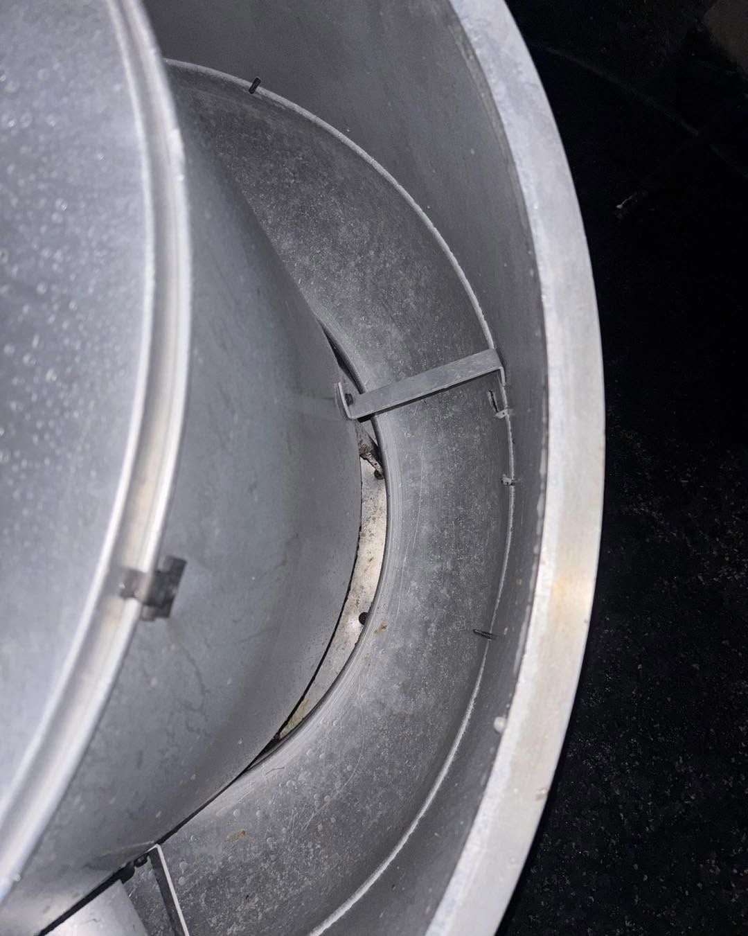 Close-up of a gray metal vent or duct with circular inner rings and a black background