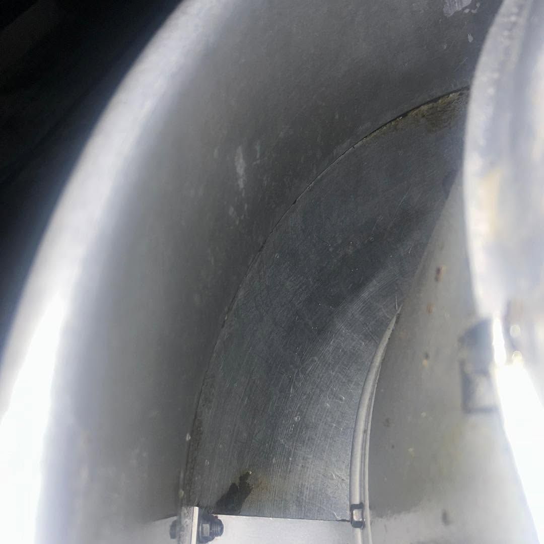 Close-up of a gray metal pipe interior with a curved seam and bright light along the edge