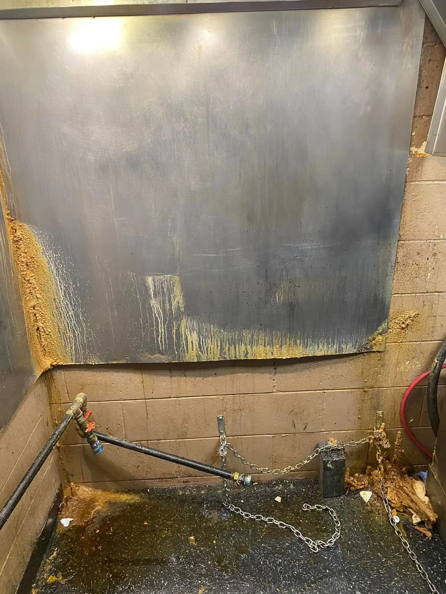 Damaged basement wall with water stains, leaking pipe, and wet floor near cinder blocks.