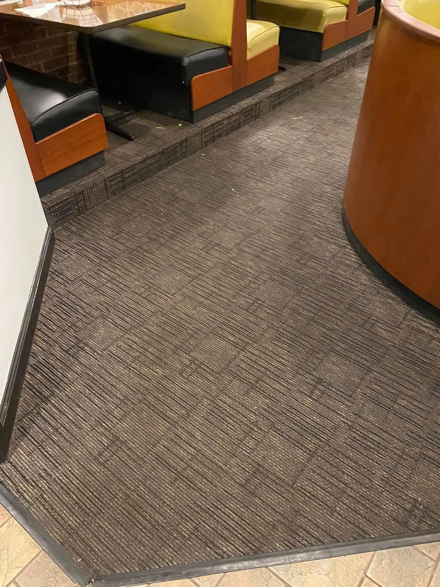 Carpeted interior with booths and a curved wooden counter or pillar in the foreground.