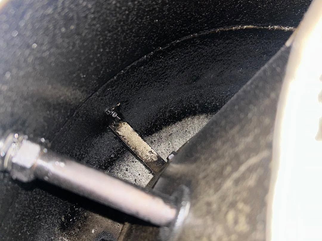 Close-up of a dark cylindrical chamber with a metal rod and dusty debris inside