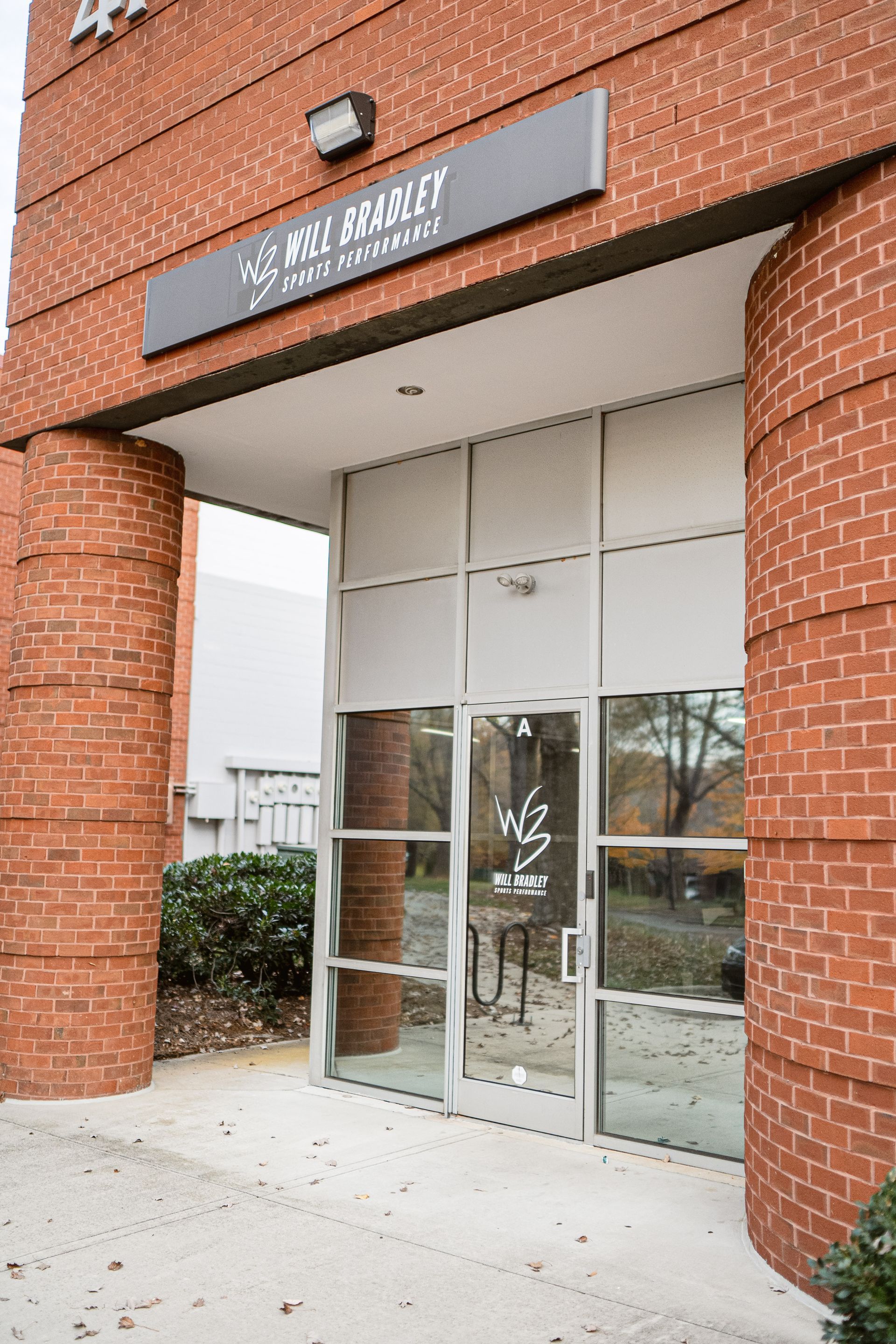 Brick storefront entrance with glass doors and a black sign above the entryway