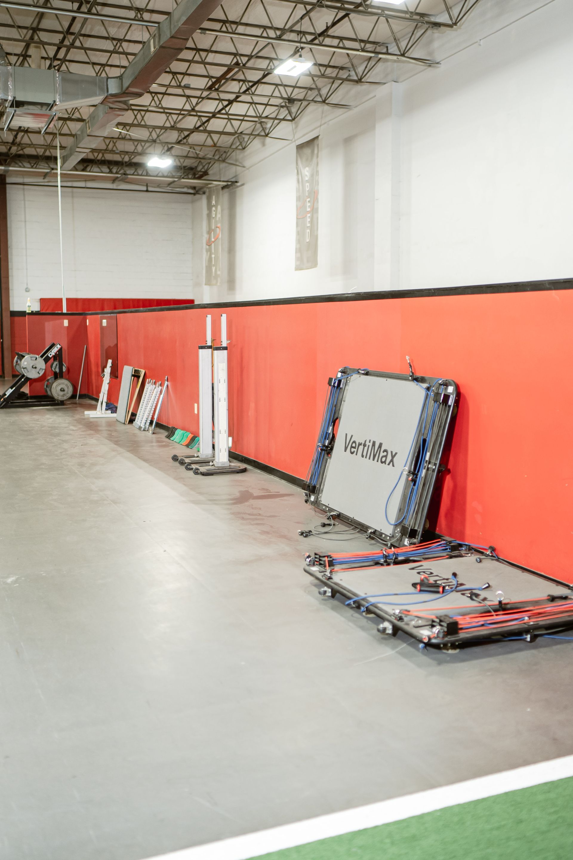 Indoor warehouse with red walls and folded gymnastics mats on the floor and leaning against the wall