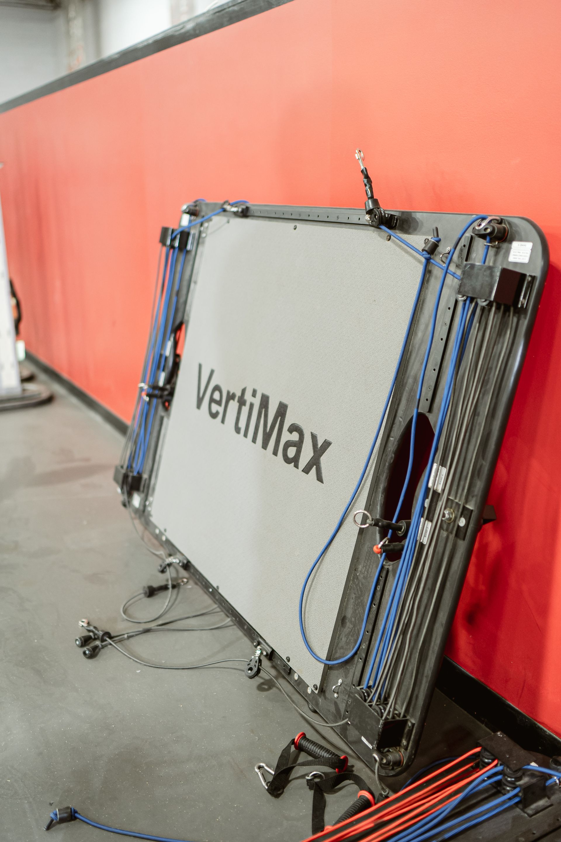 VertiMax training equipment leaning against a red wall in a gym