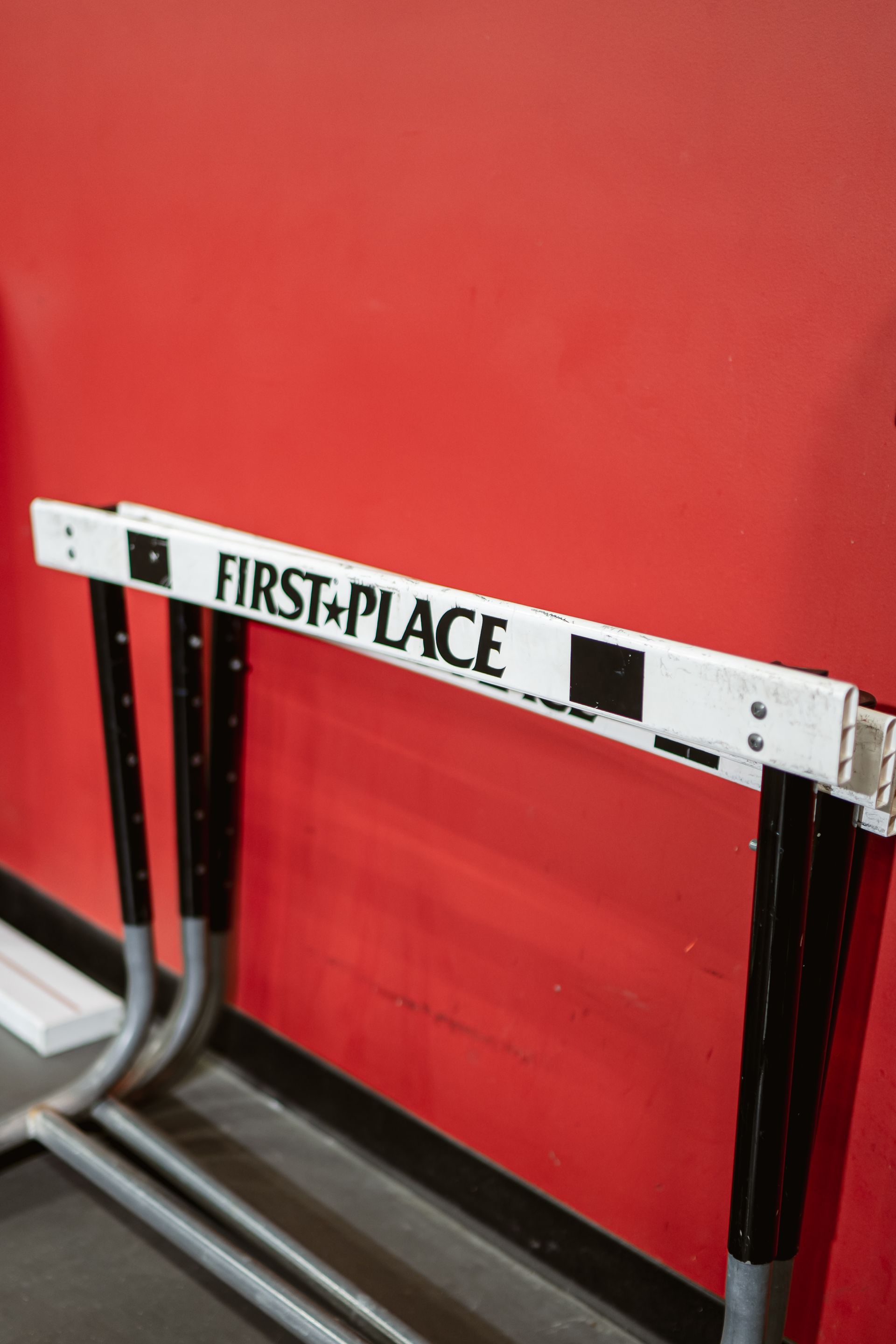 FIRST PLACE hurdle on a track against a red wall