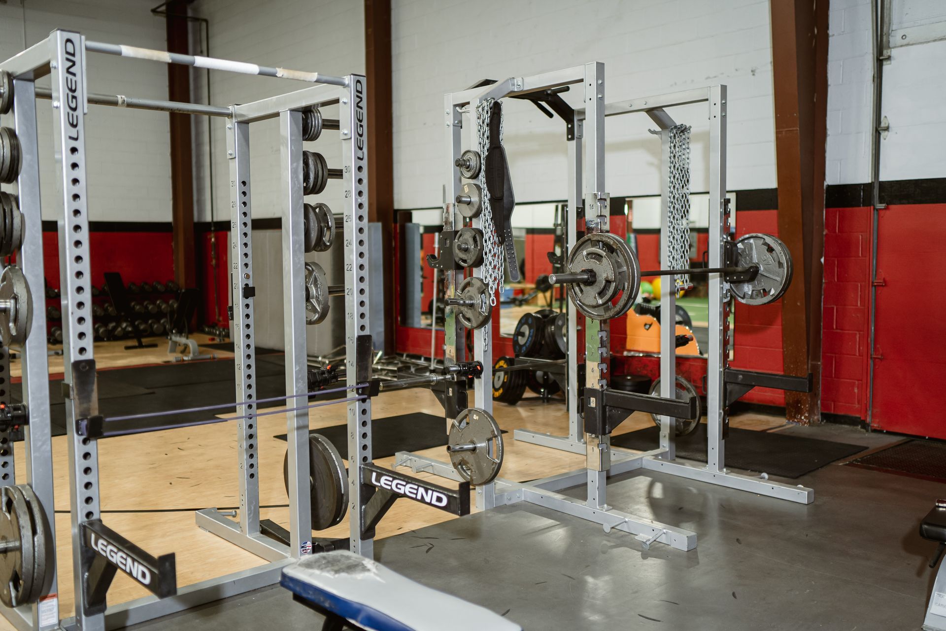 Gym with weightlifting racks, barbells, and red-and-white walls
