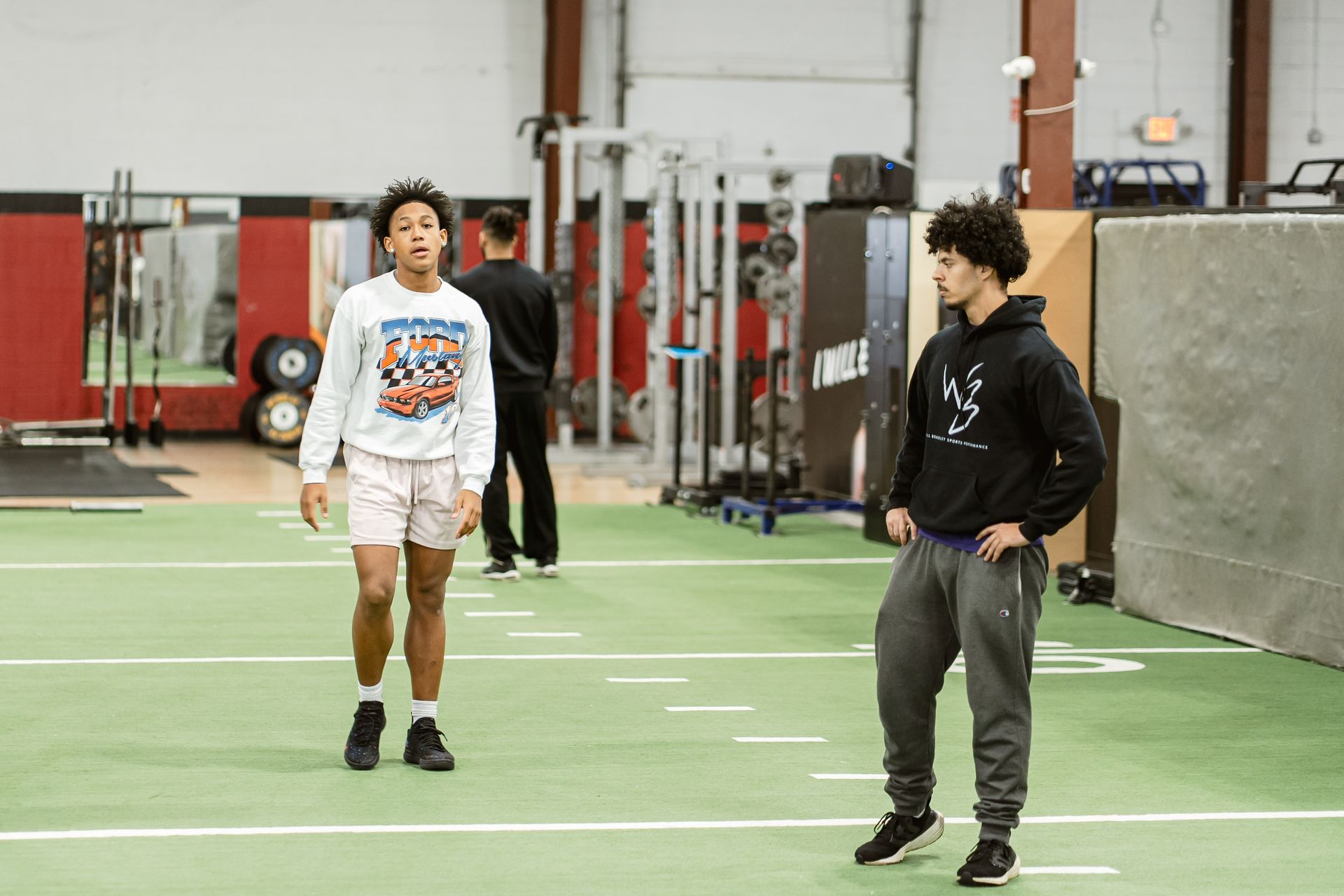 Two athletes standing on an indoor turf field during training