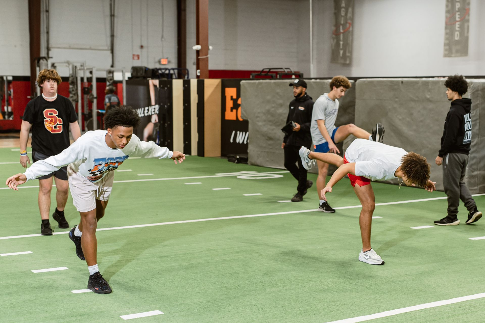 Athletes stretching on an indoor turf field during practice