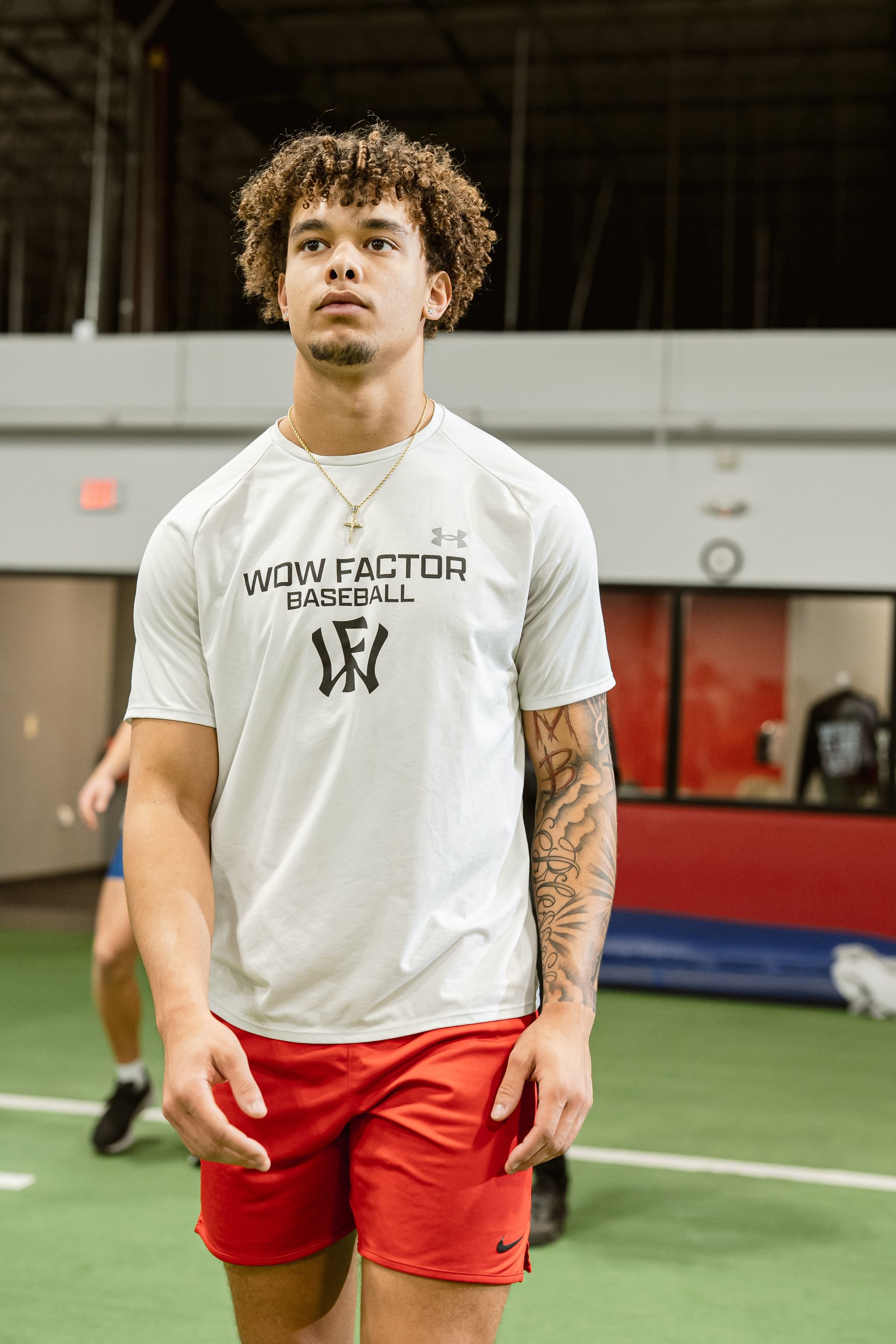 Athlete in white shirt and red shorts standing on indoor turf field