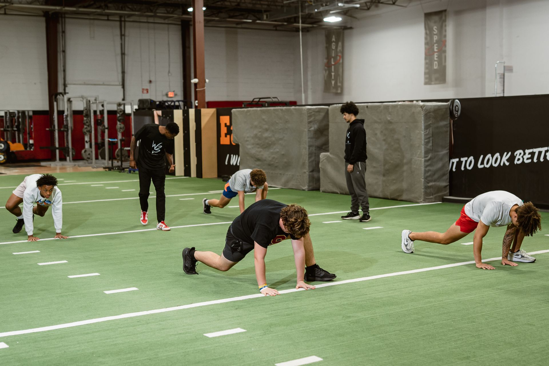 People stretching on an indoor turf field during a workout session.