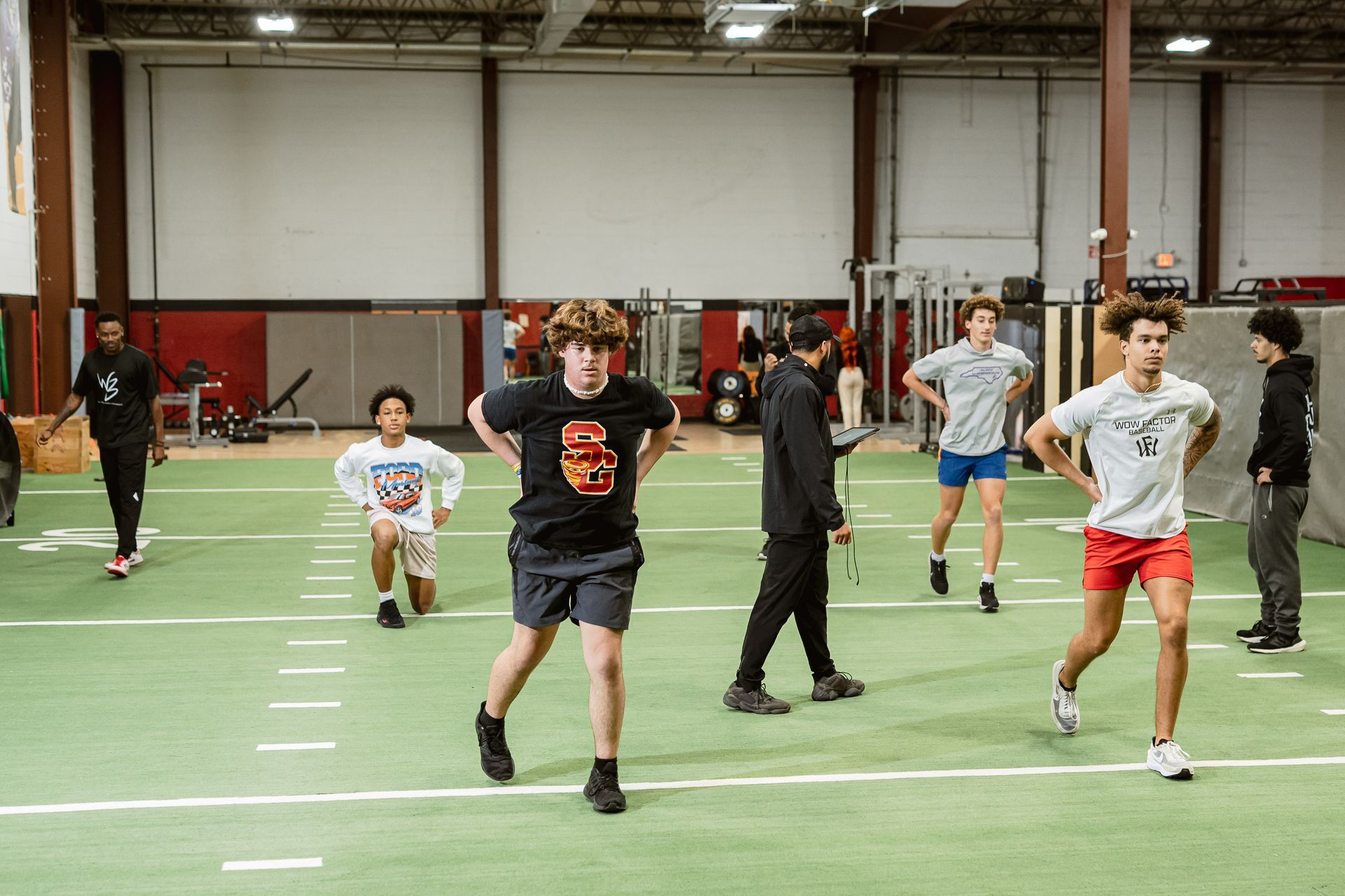 Children running on an indoor turf field, with cones and other players in the background.