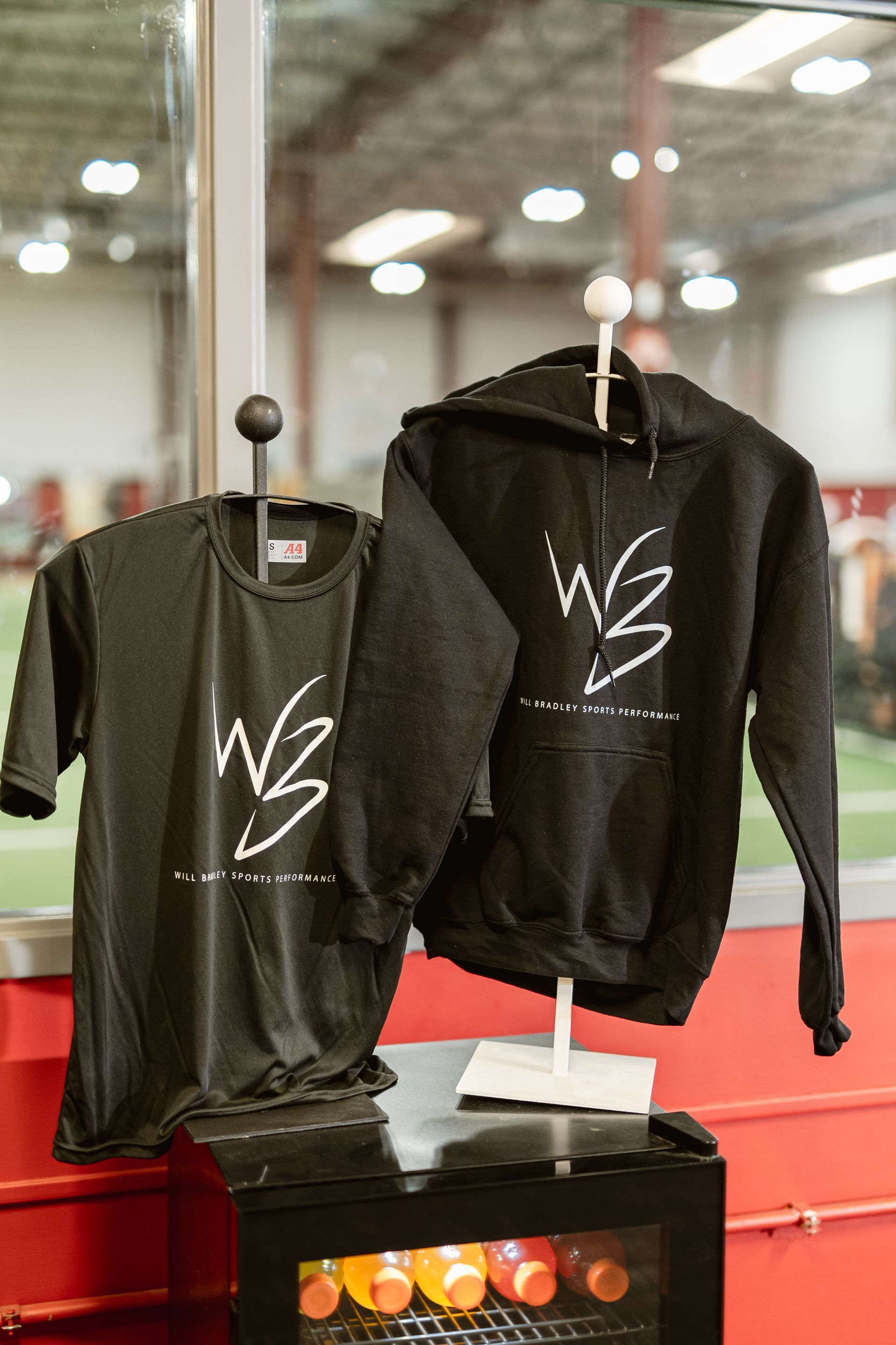 Black T-shirt and hoodie with white logo displayed on mannequins in a store.