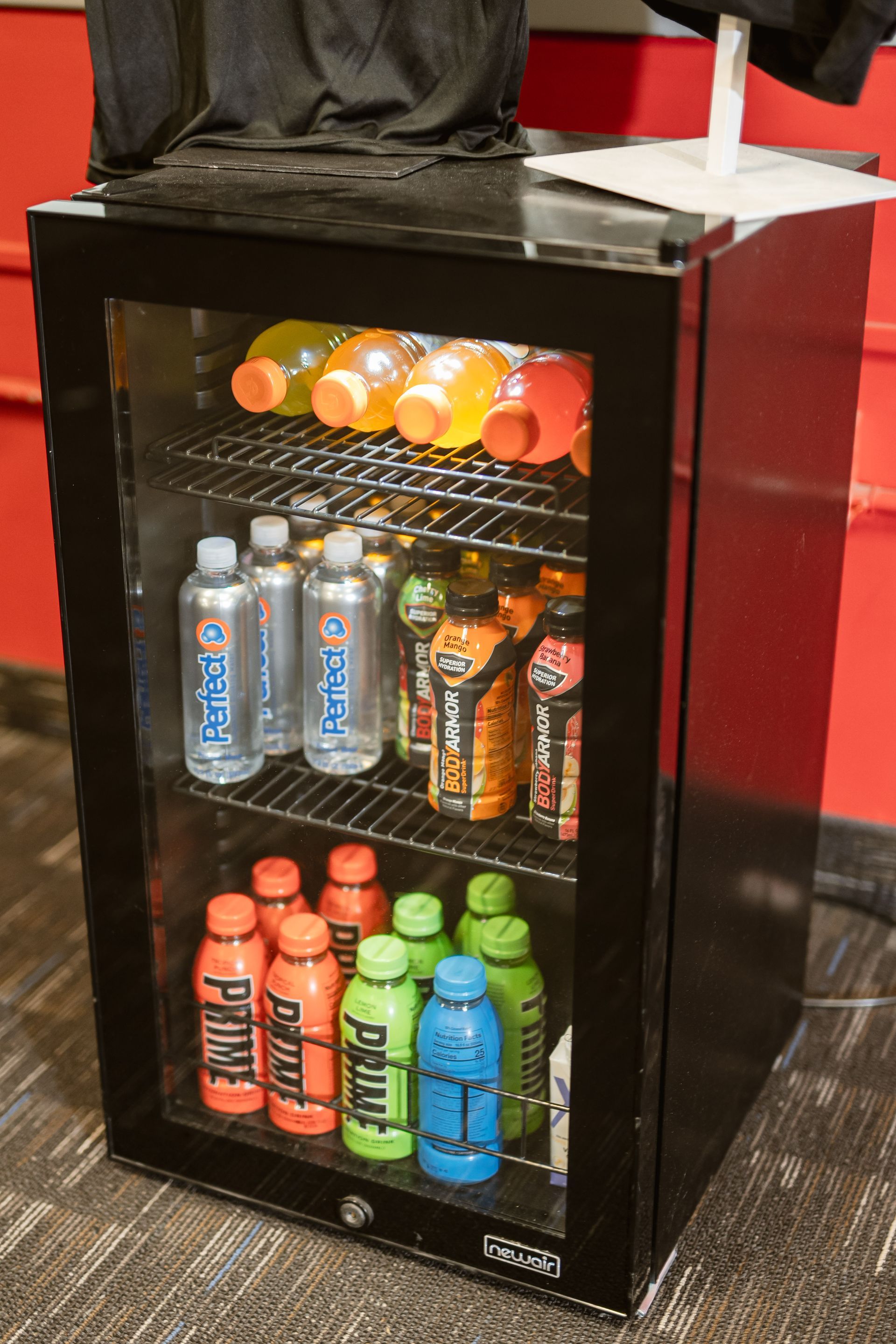 Small black beverage cooler stocked with assorted sports drinks and bottled water.