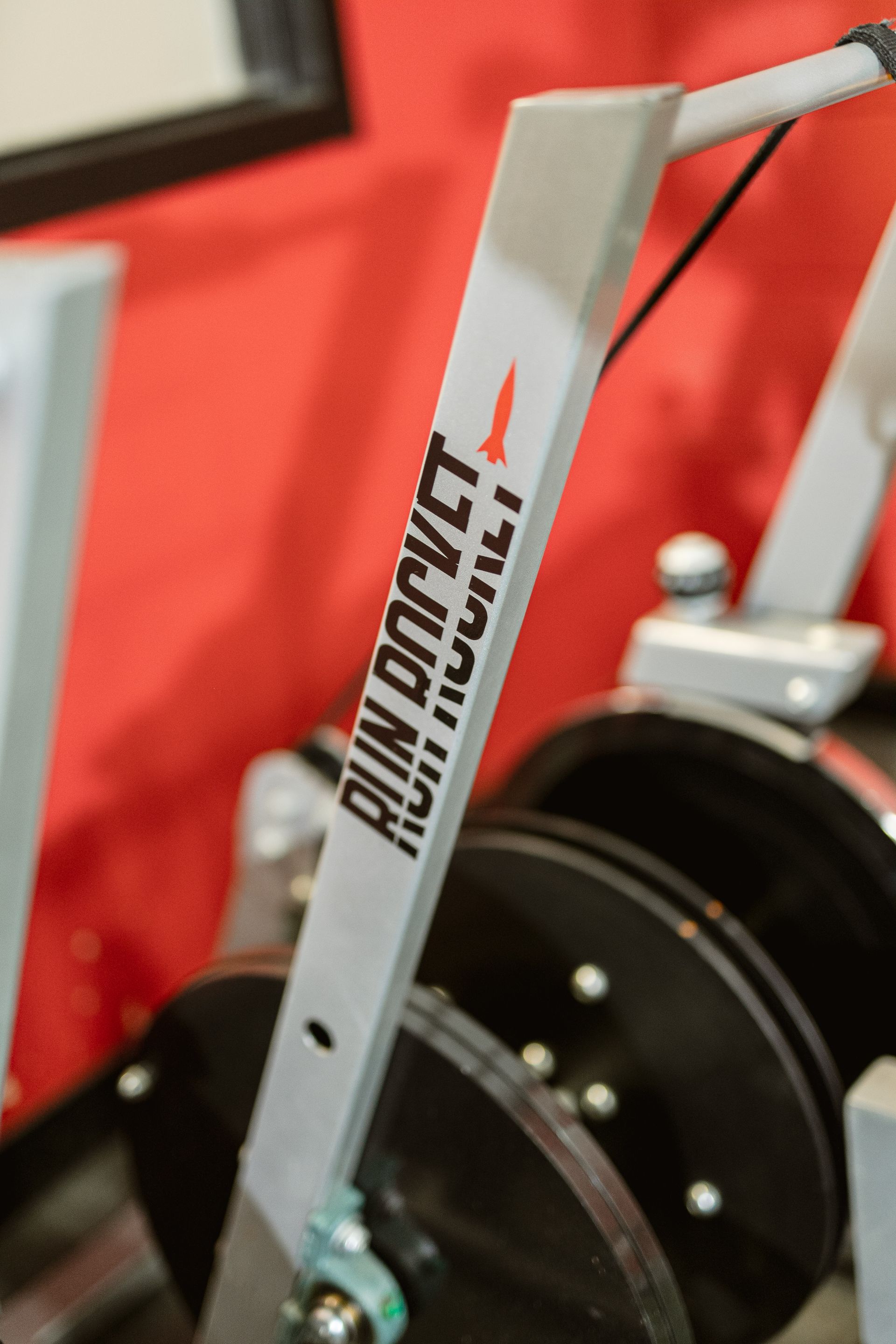 Close-up of a gray rowing machine handlebar with black flywheel in a gym