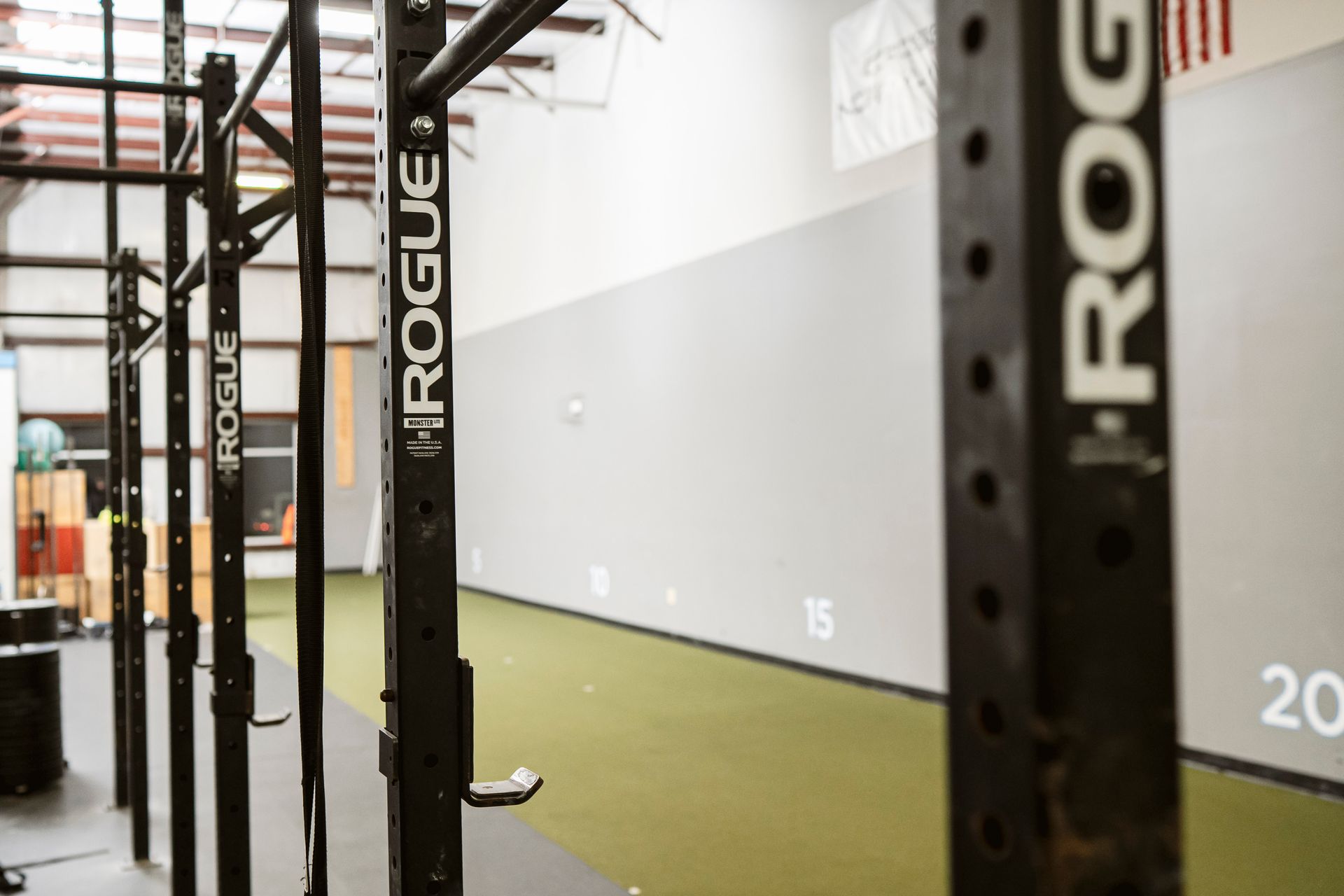Empty gym with black squat racks and green turf lanes.