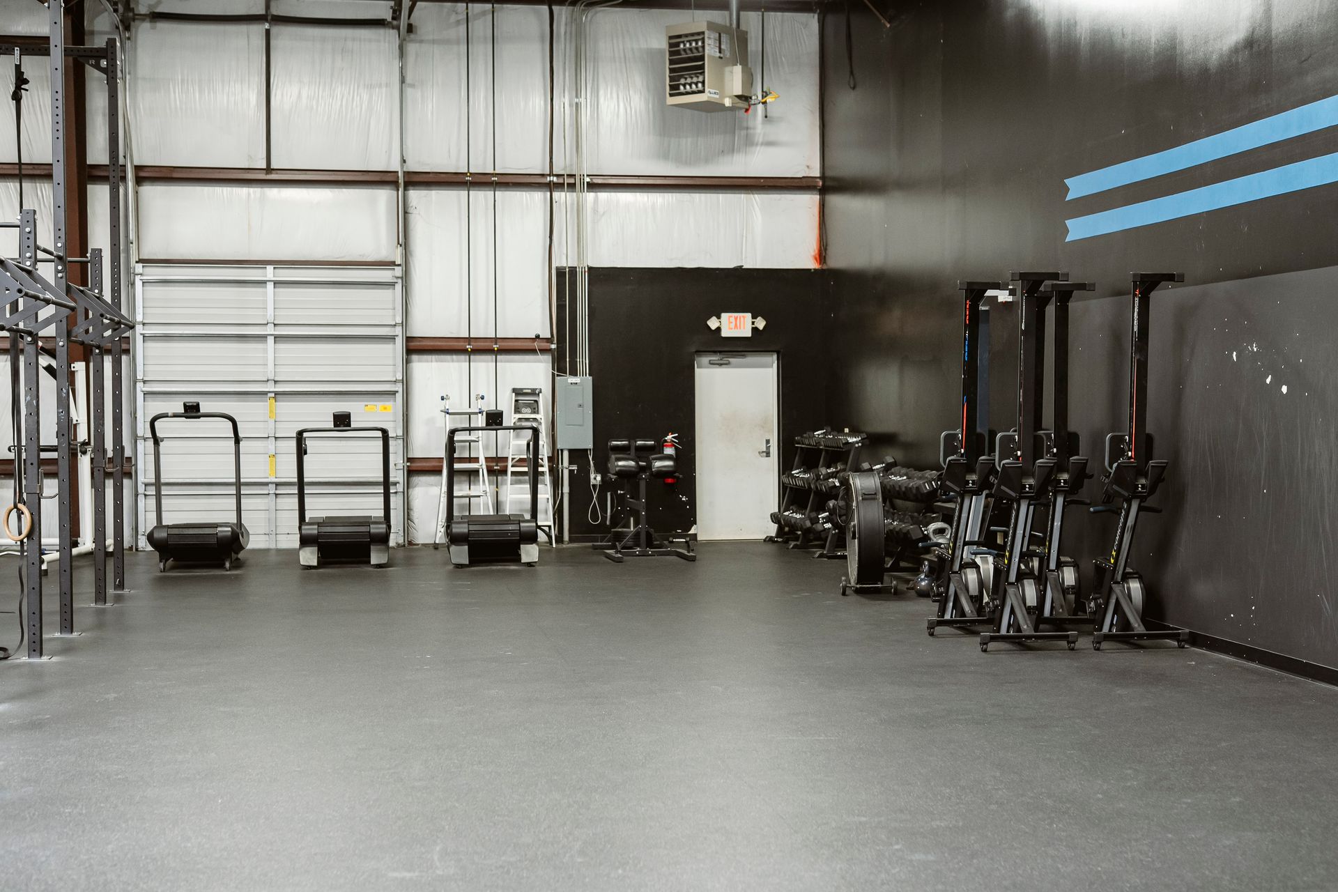 Industrial gym with exercise equipment and carts in a large warehouse-like room
