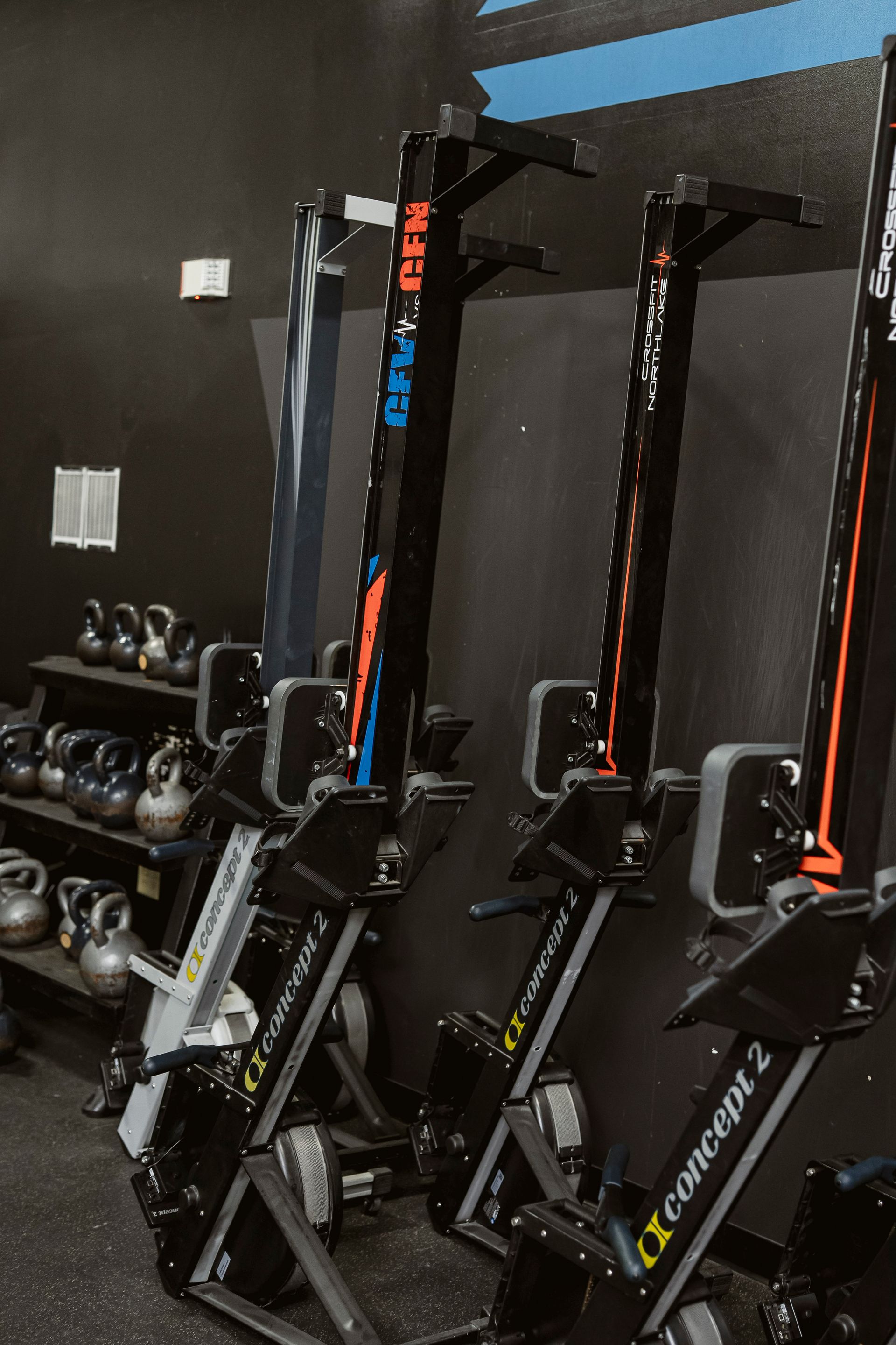Row of black stationary exercise bikes and kettlebells in a gym