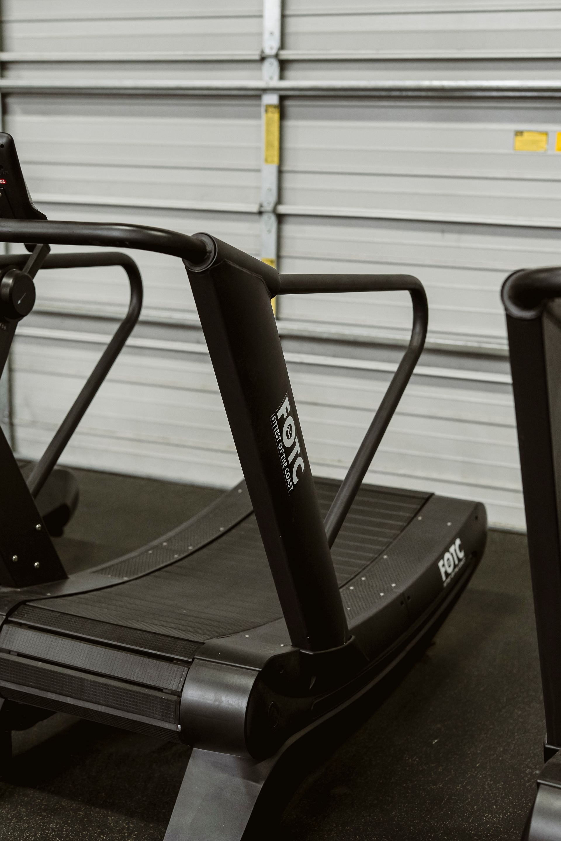 Treadmills in a gym or storage area, with black frames against a gray garage door background