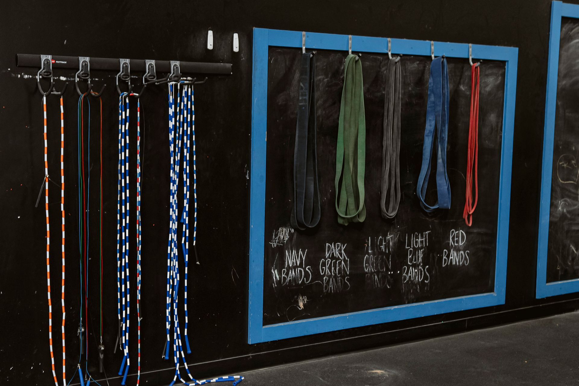 Wall-mounted display of hanging ropes and straps in black and blue-framed storage panels