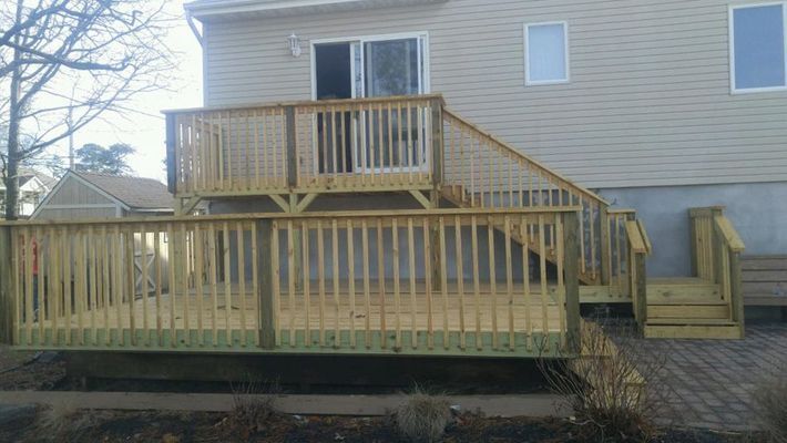 Wooden multi-level deck attached to a house with stairs and railings.