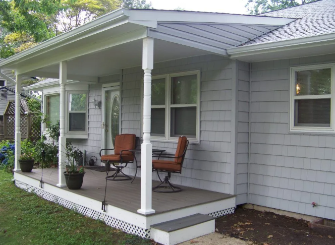 A house with a front porch; gray siding, white trim, chairs, and potted plants.