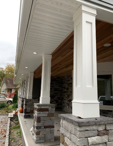 White columns on stone bases support a porch roof with wood ceiling. Exterior view.