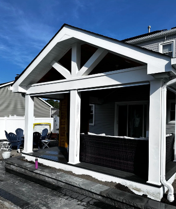 Covered outdoor patio with white trim and dark wicker furniture.