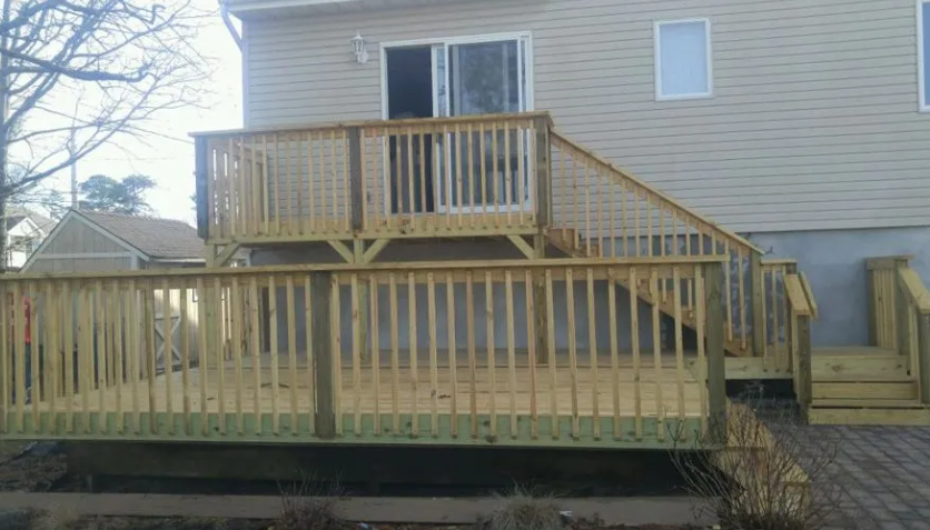 Wooden deck with stairs leading to a sliding door and a lower level.
