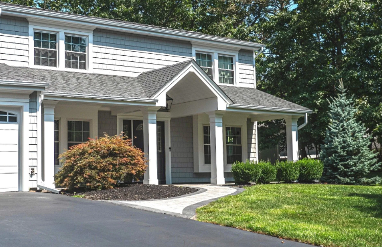 Two-story gray house with white trim. Front porch has columns, walkway leads from driveway.