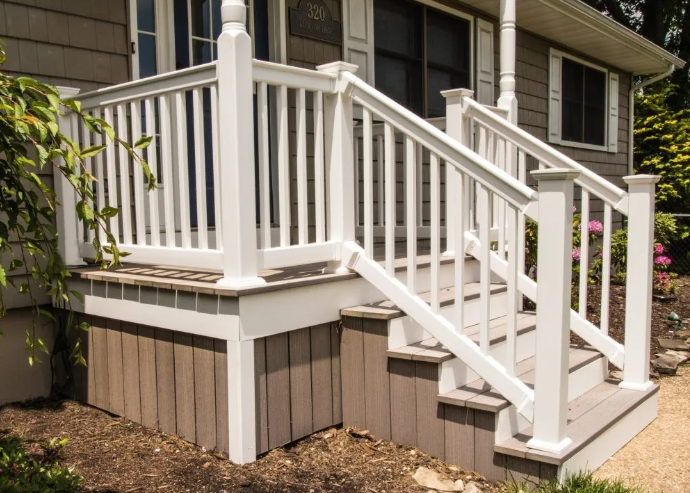 White railing on a small front porch with steps; tan siding on the house and base.