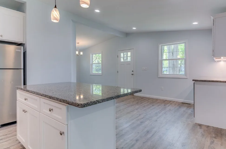 Kitchen with white cabinets, granite countertop, stainless steel refrigerator, and hardwood floors.