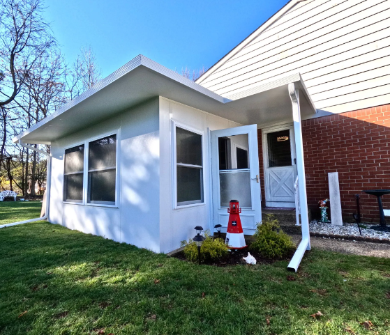 White building with windows, a door, and a red and white lighthouse decoration on the lawn.